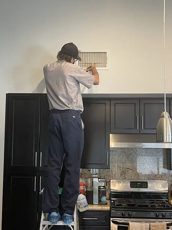Technician inspecting an air vent during HVAC service in Maple Grove